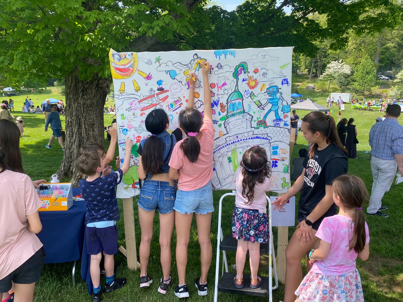 Kids drawing on a paper mural on the town green.
