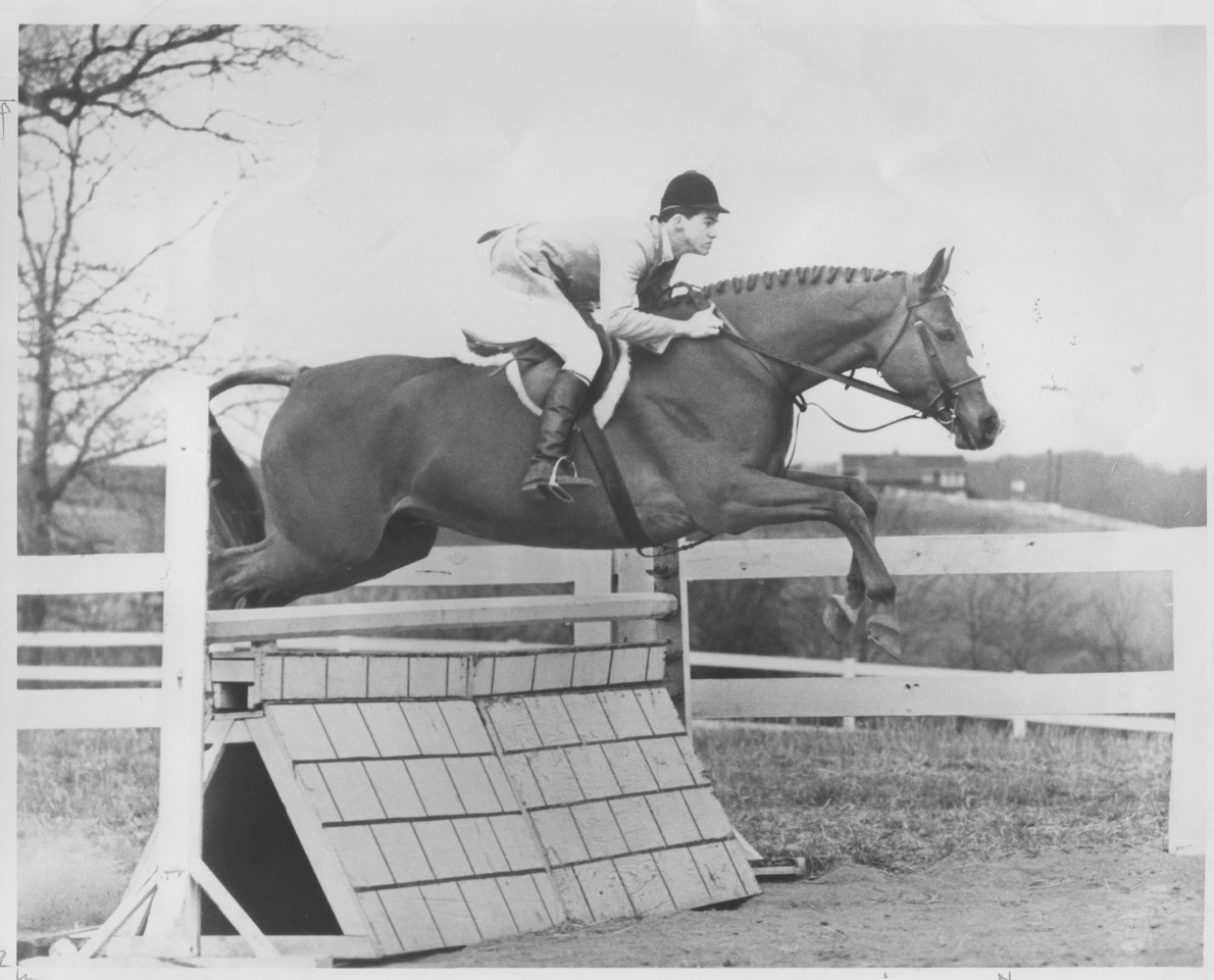 Horse and rider jumping over a tall hurdle.