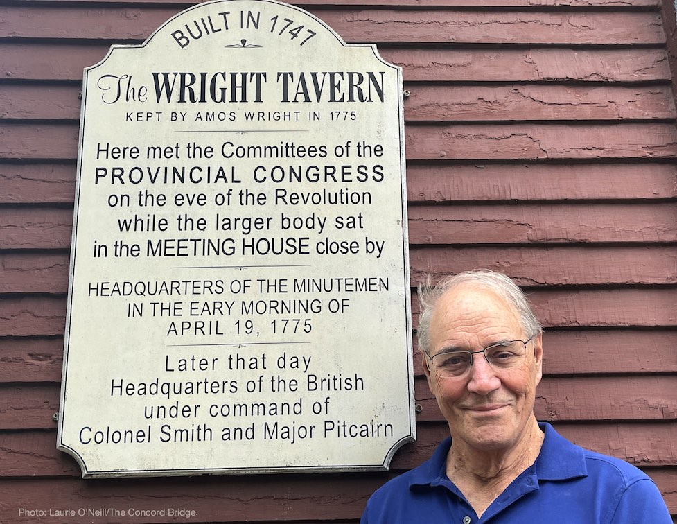 Tom Wilson standing by placard on exterior of Wright Tavern explaining its history.